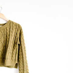 Wall Mural - Front view of beauty trendy green female sweater on hanger near white background. Fashion concept.