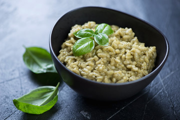 Wall Mural - Black bowl with spinach risotto, selective focus, horizontal shot