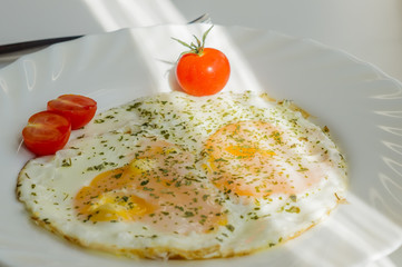 fried eggs on a plate with tomatoes and chopped parsley