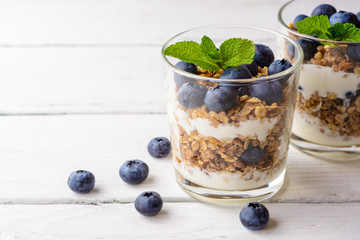 Wall Mural - Granola with yogurt and blueberries in glass on white wooden table.