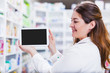 © Karanov images - Female pharmacist holding a digital tablet smiling focus on hands and tablet screen