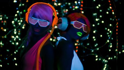 Wall Mural - two female gogo ravers in fluorescent costume dancing in disco setting