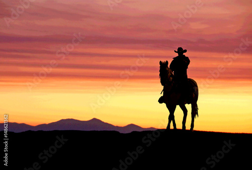 Cuadros en Lienzo Cowboy on horse at sunset in the American West