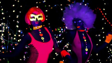 Wall Mural - two female gogo ravers in fluorescent costume dancing in disco setting