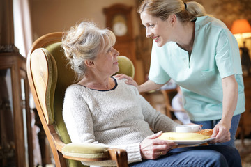 Nurse bringing breakfast to senior female patient