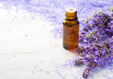 Fototapeta  - Lavender essential oil,   sprigs of lavender and  mineral bath salts on  the wooden table.  Selective focus