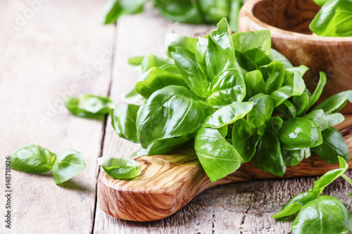 Fotografía Fresh green basil in olive mortar with pestle, vintage wooden background, rustic
