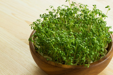 Green leaves of watercress salad in a wooden bowl. Selective focus.