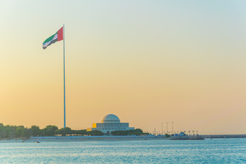 Wall Mural - A giant flagpole with the national theater of the United Arab Emirates during sunset in Abu Dhabi