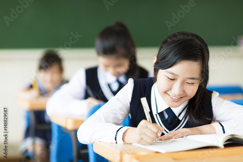 Fototapeta smiling student girl in classroom and her friends in background