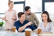 © LIGHTFIELD STUDIOS - group of young business people looking at colleague on small business meeting