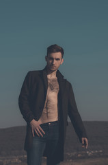 Wall Mural - Sexy man posing in unbutton coat with naked, hairy torso