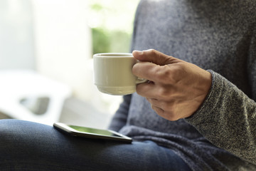 Wall Mural - young man with a coffee using a smartphone