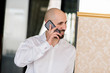 © fotofrol - A brutal bald man talking on the phone.