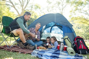 family having snacks and coffee outside the tent