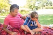 © WavebreakMediaMicro - Father consoling his son at picnic in park