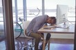 © wavebreak3 - Tired businessman napping on desk seen through glass