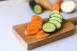 Vegetables on the cutting board. Slices of vegetables on the board isolated on a white background. Cucumber, carrot on a white background. Vegan. Healthy life and eating. Salad.