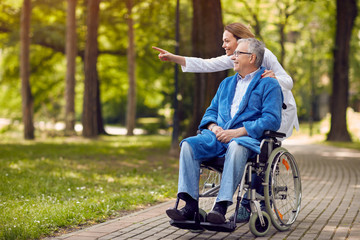 Wall Mural - nurse showing something to elderly man on wheelchair..