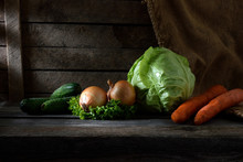 Still Life With Vegetables. Cabbage, Carrots, Onions, Cucumbers, Parsley On Wooden Background With Beautiful Sun