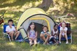 © WavebreakMediaMicro - Cheerful children sitting outside tent at campsite