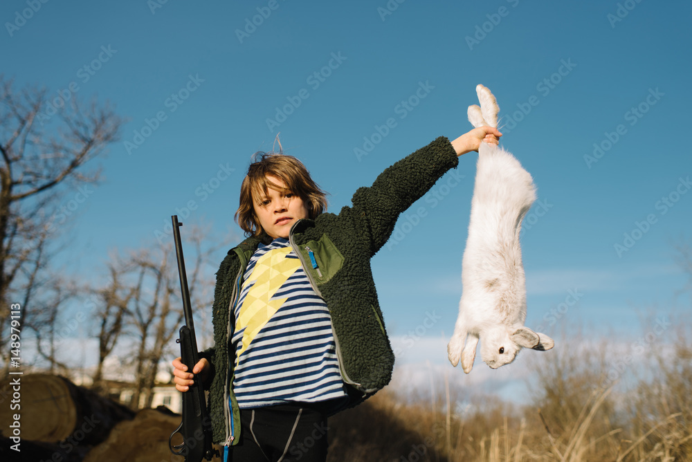 Boy holding up dead rabbit and holding a rifle Stock Photo | Adobe Stock