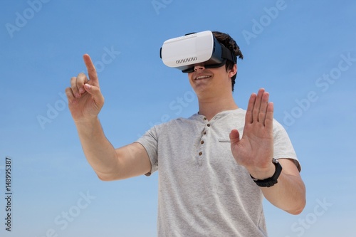 Fotografie, Obraz Man using vr headset against the blue sky
