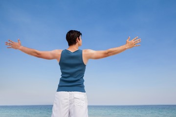 Wall Mural - Man standing at beach with arms outstretched