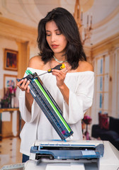 Beautiful woman fixing a photocopier and smiling during maintenance using a screwdriver