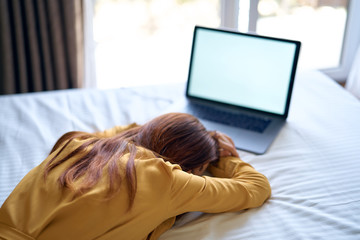 tired woman sleeps on the bed in front of laptop