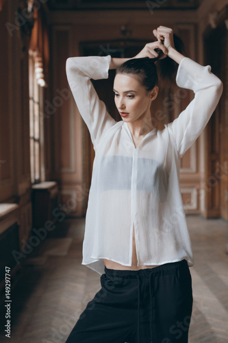 Sexy Model In White Blouse Standing Next To The Window And Holding