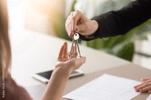 Cuadros en Lienzo Young lady taking keys from female real estate agent during meeting after signing rental lease contract or sale purchase agreement