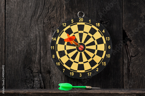 Dartboard Hanging On Old Wooden Wall With Red Dart Hit At Target
