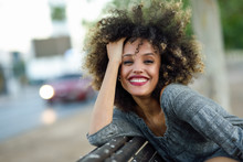 Young Black Woman With Afro Hairstyle Smiling In Urban Background