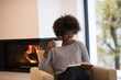 © .shock - black woman reading book  in front of fireplace