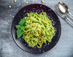 Wall Mural - Tagliatelle pasta with pesto sauce, pine nuts and parmesan on black plate.