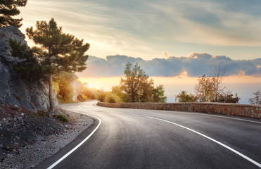 Wall Mural - Asphalt road. Landscape with rocks, sunny sky with clouds and beautiful mountain road with a perfect asphalt at sunrise in summer. Vintage toning. Travel background. Highway in european mountains