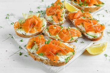 Wall Mural - Smoked salmon bruschettas with soft cheese and cucumber shavings on white board.