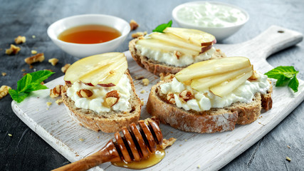 Wall Mural - Appetizer bruschetta with pear, honey, walnut and cottage cheese on white board.