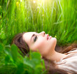 Beauty woman lying on the field in green grass. Enjoying nature
