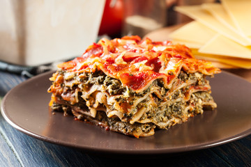 Wall Mural - Piece of tasty hot lasagna with spinach on a plate