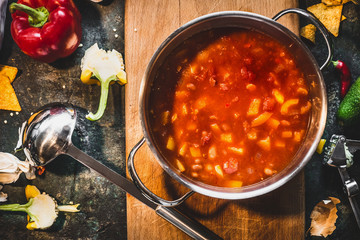 Wall Mural - Hot Mexican spicy soup in cooking pot with ladle on rustic kitchen table background, top view.