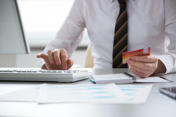 Businessman holding credit card and using laptop.