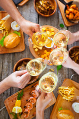 Wall Mural - Hands with red wine toasting over served table with food.