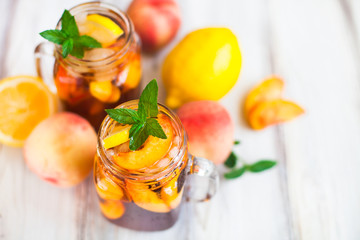 Homemade lemonade with ripe  peaches and fresh mint. Fresh peach ice tea on white wood table. Copy space background.