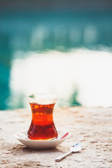Wall Mural - Hot turkish tea outdoors near water. Turkish tea and traditional turkish culture concept