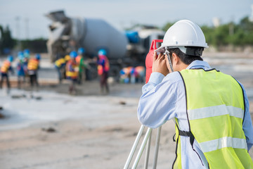 Surveyor worker using theodolite transit equipment at construction site outdoors