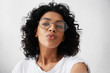 © wayhome.studio  - Young attractive African woman posing with kiss on her lips, wearing trendy spectacles, having flirty look feeling confident and beautiful. Charming dark-skinned girl with Afro hair having fun indoors