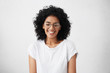 © wayhome.studio  - Portrait of charismatic and charming young African woman with curly hair wearing sylish spectacles, smiling widely, narrowing her eyes in expectation of surprise from her boyfriend, looking happy
