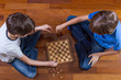 Kids playing chess sitting on wooden floor. Top view. Game, education, lifestyle, leisure concept